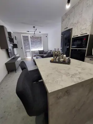 a kitchen and living room with a counter and chairs at Апартамент Слави in Blagoevgrad