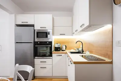 a kitchen with white cabinets and a stainless steel refrigerator at 1BD Elegance on Vasil Levski Boulevard by Flat Mаnager in Sofia