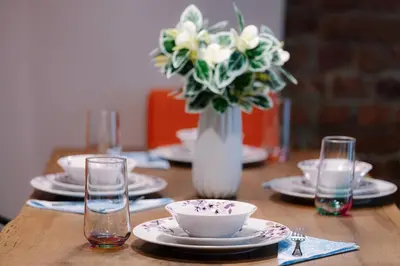 a wooden table with plates and a vase of flowers at Top Central Design, 2 Bedroom, NDK, FREE Secured parking in Sofia
