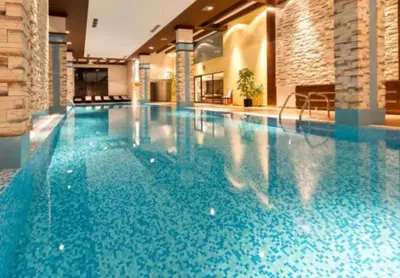 a large swimming pool with blue water in a building at Apartament by Zenit in Terra Complex C30 in Razlog