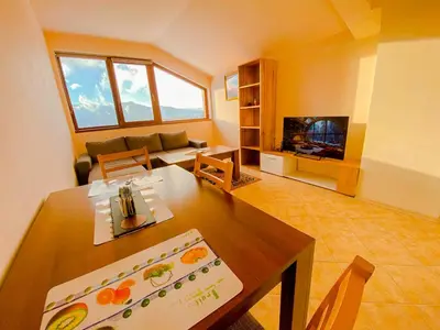 a living room with a table and a tv at Panorama View-Stoykite in Stoykite