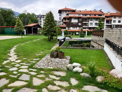a garden with grass and rocks and a building at Ski Lift Studio 531 in Bansko