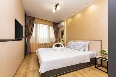 a bedroom with a large white bed and a television at Duos of Delight Matching Urban Apartments for Your Plovdiv Adventure by Flat Mаnager in Plovdiv