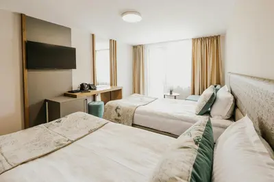 a hotel room with two beds and a television at Hotel Green Park Service Perfected in Garmen