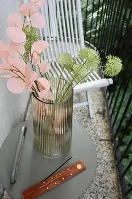 a vase with pink flowers on a table next to a chair at #Maison\u32b6 - A Vibrant, Urban Stay in Sofia