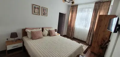 a bedroom with a bed with pink pillows and a television at АПАРТАМЕНТ ЮЛИЯ ДЕЛУКС I in Velingrad