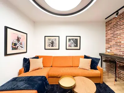 an orange couch in a living room with a fireplace at 2BR by NDK - AC - Desk - Lux Interior - Balcony in Sofia