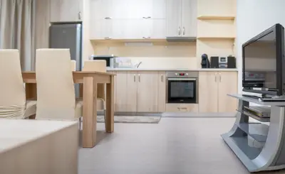 a kitchen with a table and a tv in it at Апартамент Амбра in Sandanski