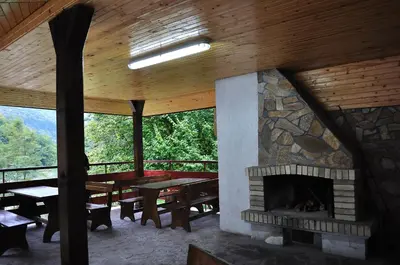 a room with a stone fireplace and a table and benches at Fisherman's Hut Family Hotel in Beden