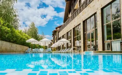 a swimming pool with chairs and umbrellas next to a building at Apartament by Zenit in Terra Complex Massonet D28 near Bansko in Razlog