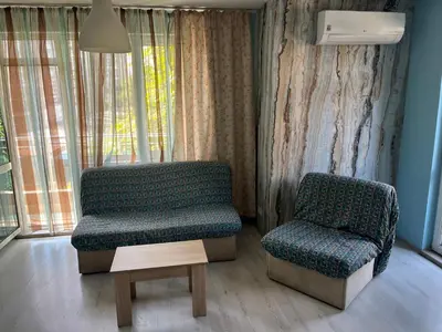 a couch and a chair in a room with a window at APARTHOTEL VICTORY SOFIA in Sofia