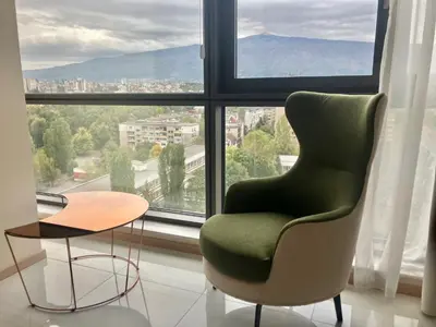 a chair and a table in front of a window at Point Sofia Grand Suite in Sofia