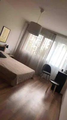 a bedroom with a bed and a chair next to a window at Specious Modern Apartment in Sofia