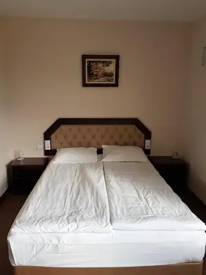 a bedroom with a bed with white sheets at Hotel Podkovata in Etropole
