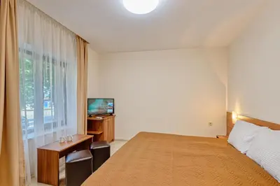a bedroom with a bed and a desk and a television at Къща за гости Relax in Hisarya