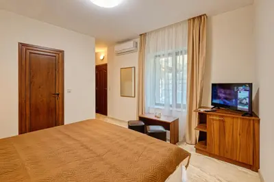 a hotel room with a bed and a flat screen tv at Къща за гости Relax in Hisarya