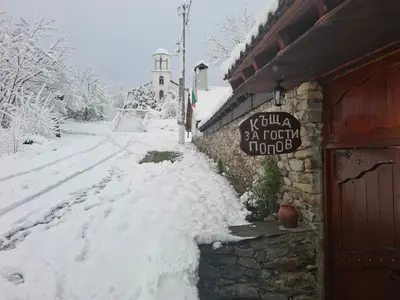 a snow covered street next to a building with a sign at Guest House Popov in Marchevo
