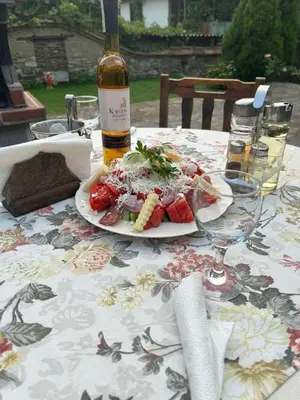 a table with a plate of food and a bottle of wine at Guest House Popov in Marchevo