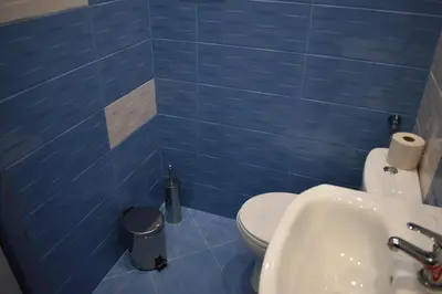 a blue tiled bathroom with a toilet and a sink at Apartment Airport Sofia in Sofia