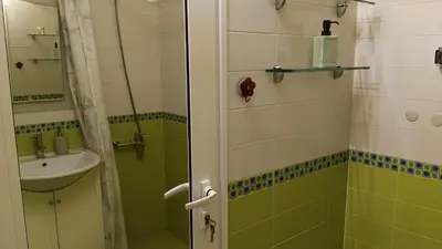 a green and white bathroom with a sink and a shower at Serenity Apt Iztok Sofia in Sofia