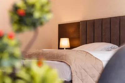 a bedroom with a bed with a headboard and a lamp at Cityscape Luxury Suites in Plovdiv