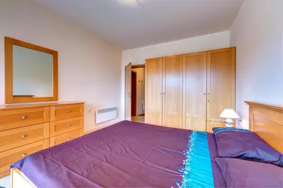 a bedroom with a purple bed and wooden cabinets at Panorama Studio in Stoykite