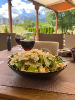 a bowl of salad and a glass of wine on a table at Cosy Appartement Green Life Bansko in Bansko