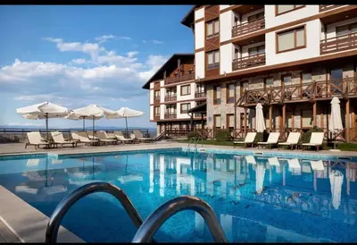 a swimming pool in front of a hotel with chairs and umbrellas at Cosy Appartement Green Life Bansko in Bansko