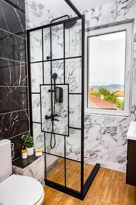 a bathroom with a shower with black and white marble walls at Forest Oasis Guest House FREE PARKING in Sapareva Banya
