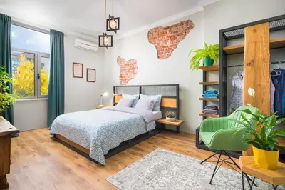 a bedroom with a bed and a green chair at Alexandra's City Center Apartment II in Sofia
