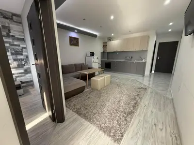 a large living room with a couch and a kitchen at Апартаменти в сърцето на парка in Sandanski