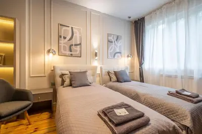 a hotel room with two beds and a chair at Calm, Luxury Apartment, Premium Location at NDK! in Sofia
