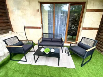 a patio with three chairs and a table on the grass at Large One Bedroom with Terrace next to the Ski Lift in Bansko