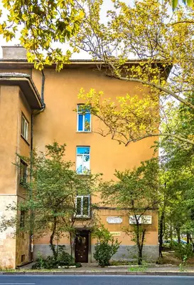 an orange building with blue windows and trees at Chic and Charming 2BD Flat in the Heart of Plovdiv by Flat Mаnager in Plovdiv