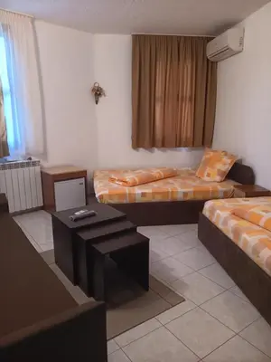 a room with two beds and a table in it at Хотел Марио in Melnik