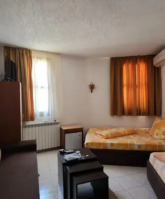 a hotel room with two beds and a table at Хотел Марио in Melnik
