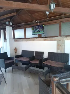 a living room with couches and a tv on the wall at Хотел Марио in Melnik