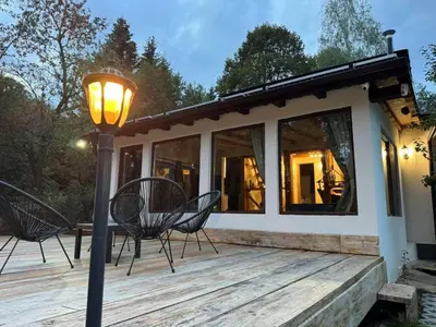 a house with two chairs and a lamp on a deck at Villa Yarema Mountain Relax with Hot Jacuzzi & Sauna by BookVillaBG in Zheleznitsa