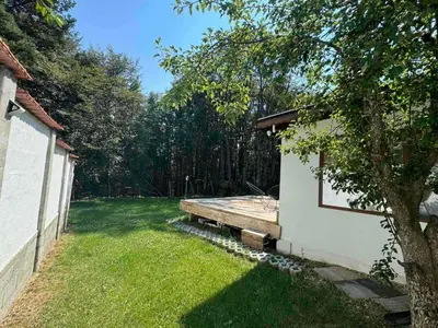 a backyard with a wooden bench next to a building at Villa Yarema Mountain Relax with Hot Jacuzzi & Sauna by BookVillaBG in Zheleznitsa