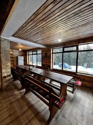 a room with a large wooden table and windows at Райски кът “Еленова поляна” in Dobărsko