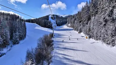 a ski lift going down a snow covered mountain at Next to the Ski Lift Downtown Bansko in Bansko