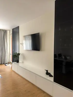 a living room with a tv on a white wall at Maryland Apartment incl Private Garage in Sofia