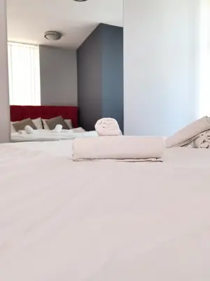 a white bed with two towels on top of it at Boutique Apartment in Plovdiv