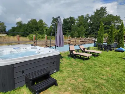 a hot tub in a yard with chairs and an umbrella at Shekerdejiiski guest house bansko in Bansko