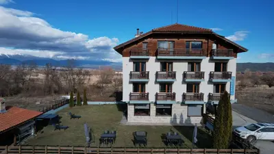 a large white building with a roof at Shekerdejiiski guest house bansko in Bansko