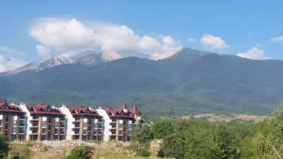 a building on a hill with mountains in the background at Belvedere Holiday Club - Mountain View in Bansko