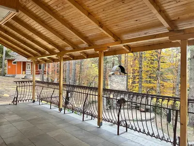 a porch with a wooden roof with a metal railing at Почивна база Пиринпласт in Gotse Delchev