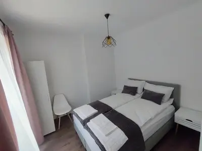 a white bedroom with a bed and a chandelier at Cozy Rooms Panagyurishte in Panagyurishte