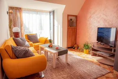 a living room with a yellow couch and a tv at Pumpkin Spiced Suite with Own Parking and Office Setup in Sofia