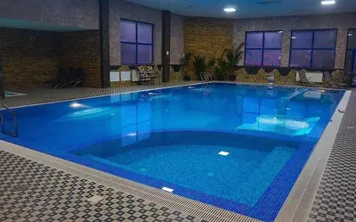 a large blue swimming pool in a building at Хотел Стиляна/Hotel Stilyana in Devin